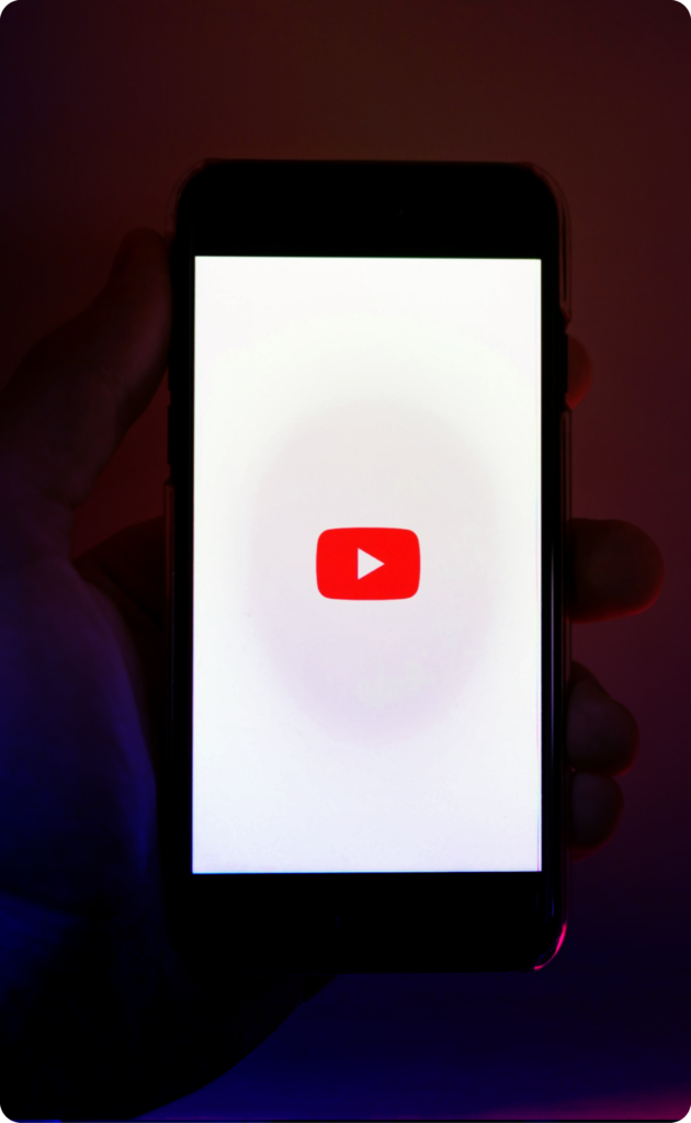 Une main tenant un téléphone avec le logo YouTube à l'intérieur