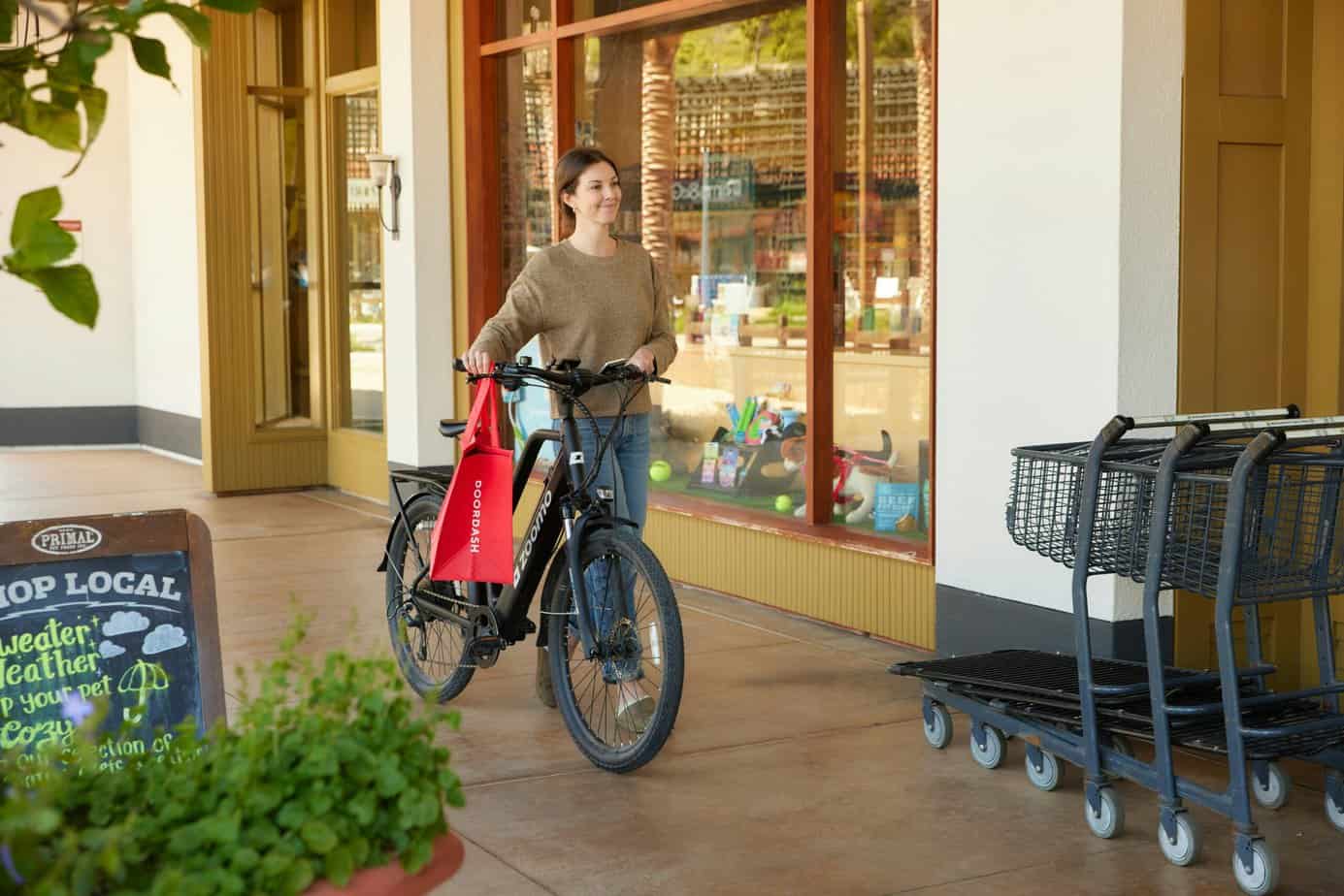Doordash Rider souriant comme son vélo Zoomo à côté d'un magasin local